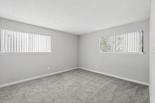 A room with two windows and carpeted floor.