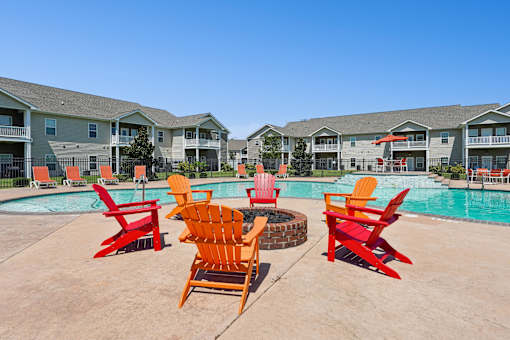 A pool surrounded by red chairs and buildings in the background. at The Lory of Greenway Village Apartments, Ky
