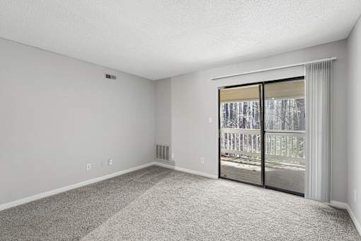A room with a sliding glass door leading to a balcony.