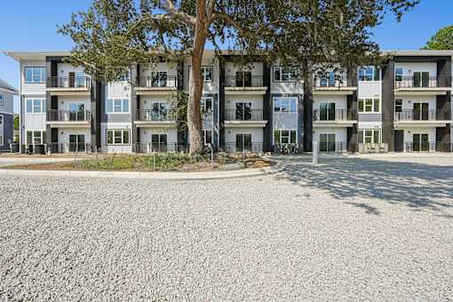 Three story apartment building with gravel parking area at The Palms Apartments, Charleston