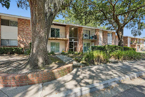 Two story brick apartment building with large tree at The Palms Apartments, South Carolina