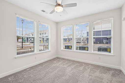 A room with a ceiling fan and three windows.