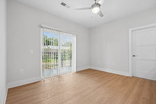 Empty bedroom with vinyl wood flooring and sliding glass door at The Palms Apartments, Charleston, SC