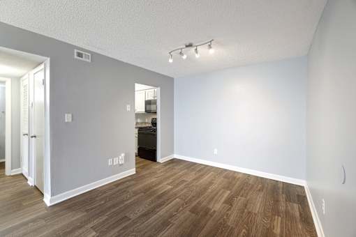 an empty living room with wood flooring and a door to a kitchen  at Governors House, Huntsville, 35805