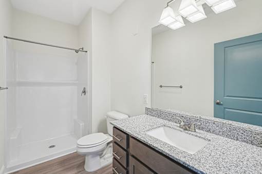 A bathroom with a white toilet, a sink, and a shower.