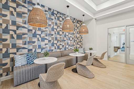 A living room with a grey couch, a white table, and a wall with a blue and brown pattern.