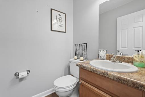 A bathroom with a toilet, sink, and a picture on the wall.