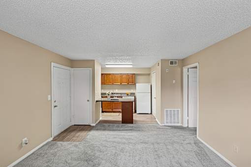 A spacious living room with a kitchen in the background.