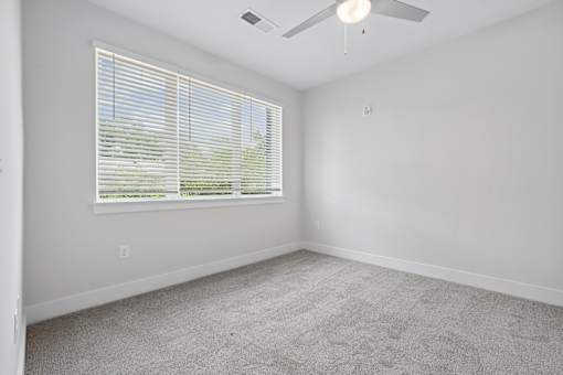 Spacious bedroom with large window and carpet flooring at The Palms Apartments, South Carolina, 29407