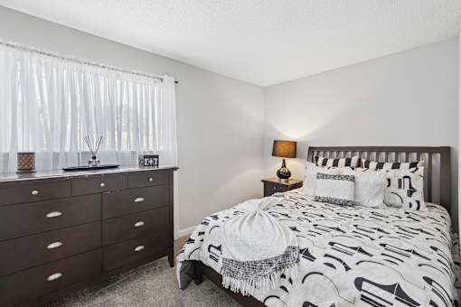 A bedroom with a bed, nightstand, and dresser.