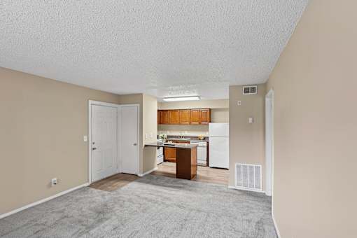A kitchen area with a refrigerator, cabinets, and a countertop.