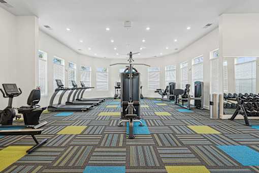 A gym with a variety of equipment including treadmills, weights, and exercise machines.
