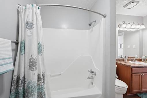 A white bathtub with a shower curtain and a towel hanging on the side.