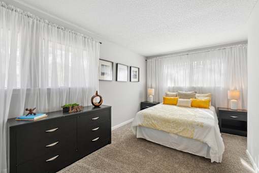 A bedroom with a bed, nightstands, and pictures on the wall.