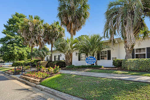 Property information center with palm trees and flower beds at The Palms Apartments, Charleston