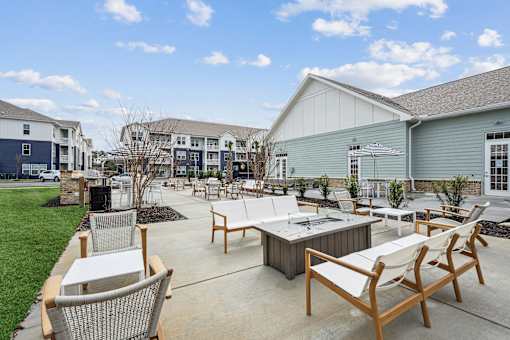 A patio with chairs and a table is surrounded by buildings.