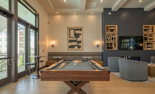 A pool table is in the middle of a room with a fireplace and a TV at The Ashton at East Park Apartments, Georgia, 30144