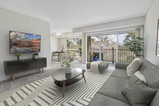 A living room with a grey couch and a painting on the wall.