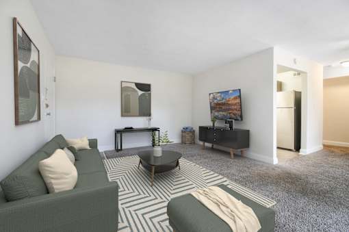 A living room with a green couch, a coffee table, and a painting on the wall.
