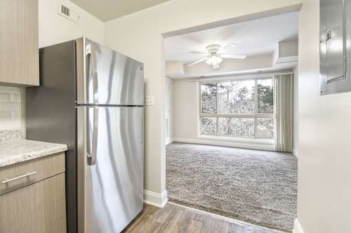 A stainless steel refrigerator in a kitchen with a window.