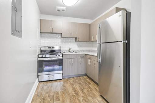 A kitchen with a stainless steel refrigerator, oven, and wooden floors.