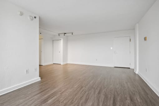 an empty living room with wood floors and white walls