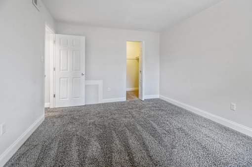 A room with a carpeted floor and two doors, one of which is open.