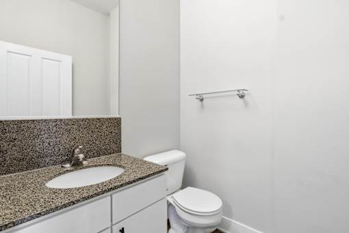 A bathroom with a toilet, sink, and mirror.