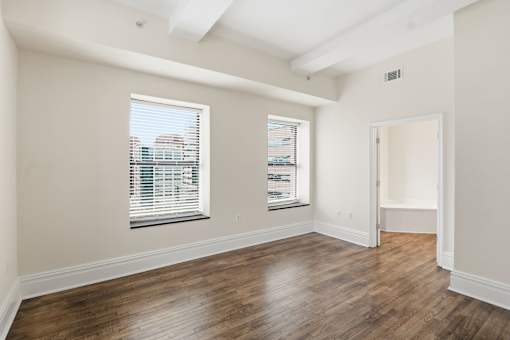 A room with wooden floors and a window with blinds.