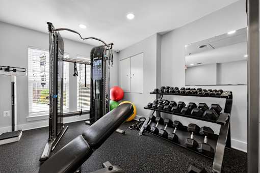 A gym with a variety of equipment including a weight bench, dumbbells, and a mirror.