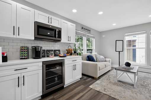 A modern kitchen with white cabinets and a black microwave.