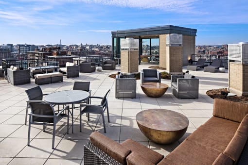 a rooftop terrace with couches tables and chairs and views of the city