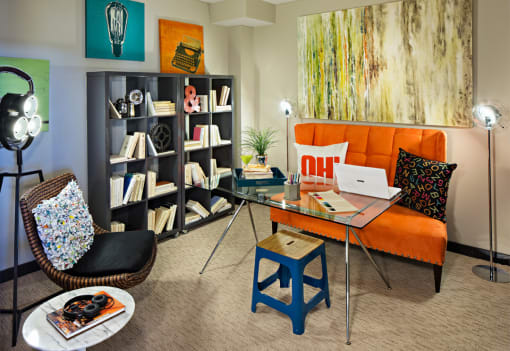 a living room with an orange couch and a desk with a laptop