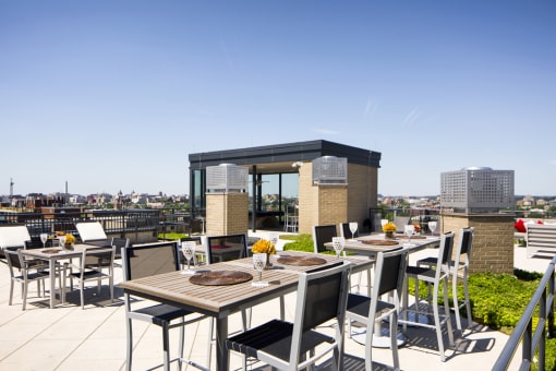 a rooftop terrace with tables and chairs and a view of the city