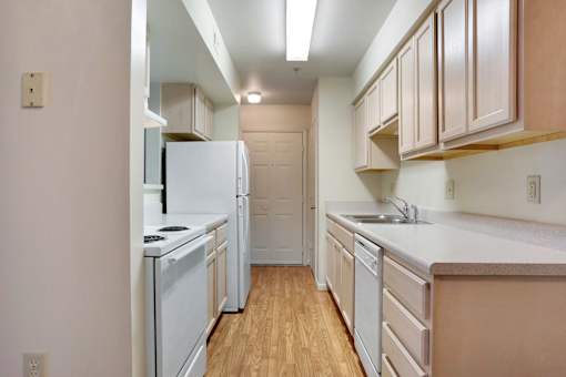 A kitchen with white appliances and wooden floors.