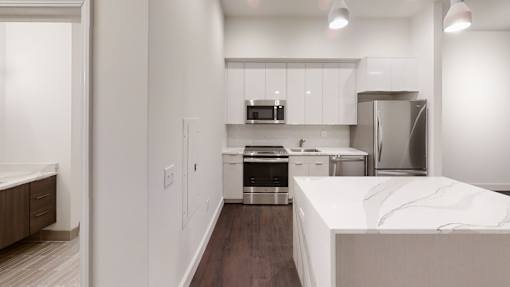 A kitchen with a white counter top and stainless steel appliances.