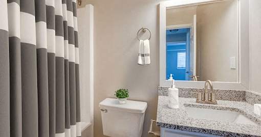 A bathroom with a white toilet, a sink, and a mirror.