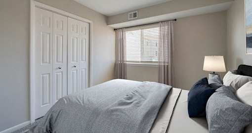 A bedroom with a large bed and a window with curtains.