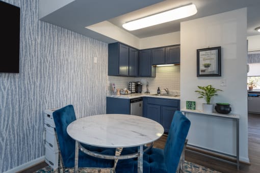 a kitchen with blue cabinets and a marble table with blue chairs