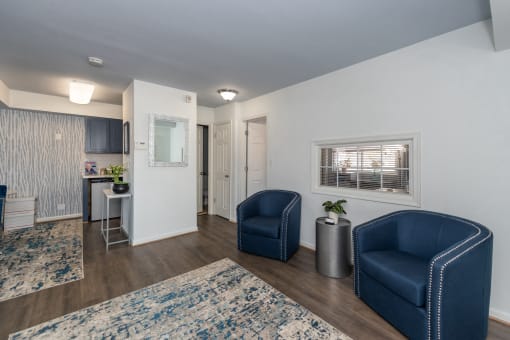 a living room with two blue chairs and a kitchen with a sink