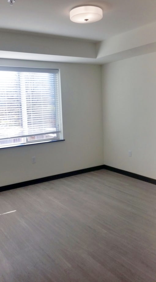 an empty room with a window and wood floors