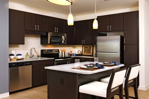 a kitchen with stainless steel appliances and a island with chairs