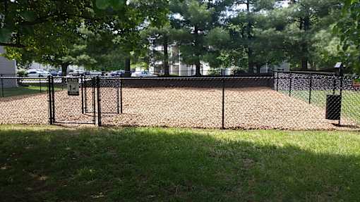 A fenced area with a gate and a trash can.