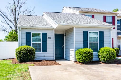 a white house with blue doors and a sidewalk in front of it