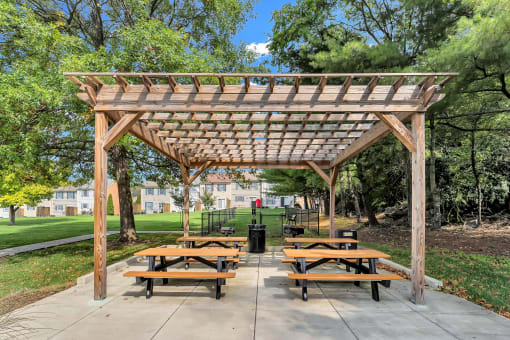 a picnic area with benches and a wooden pavilion
