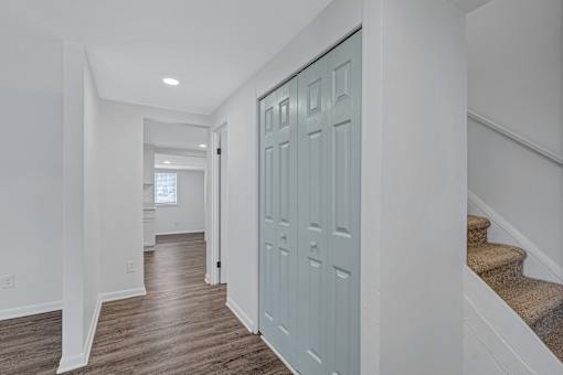 A hallway with a blue door and wooden floors.