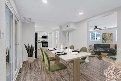 A modern dining room with a white table and green chairs.