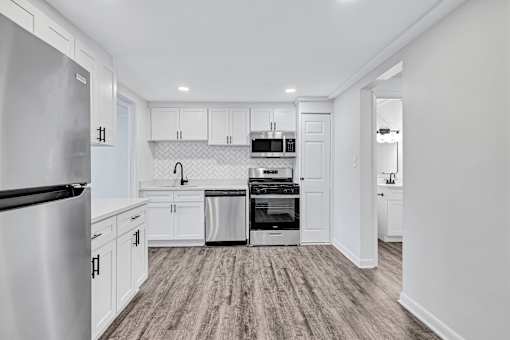 A kitchen with a refrigerator on the left and a dishwasher on the right.