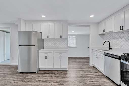 A modern kitchen with white cabinets and a wooden floor.