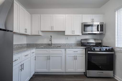 A kitchen with white cabinets and a black stove.